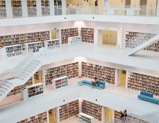 An interior view of a modern multi-level building with white stairs and open shelves.